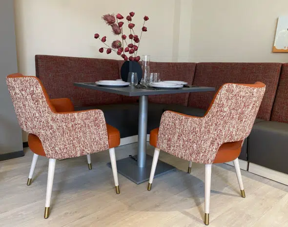 Table à hauteur variable, banquettes et chaises avec accoudoirs dans la salle à manger d'un EHPAD