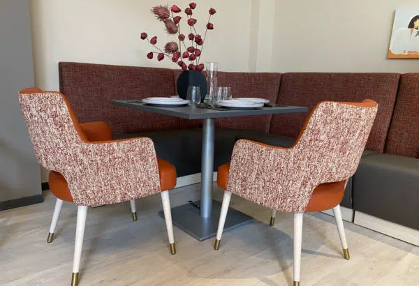 Table à hauteur variable, banquettes et chaises avec accoudoirs dans la salle à manger d'un EHPAD